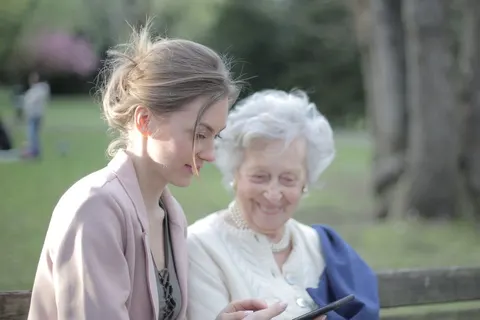 A daughter shows her mother how to use a smartphone.